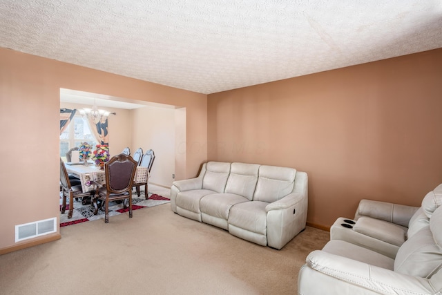 carpeted living area featuring a notable chandelier, visible vents, a textured ceiling, and baseboards