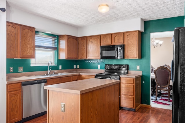 kitchen featuring black appliances, dark wood finished floors, light countertops, a textured ceiling, and a sink