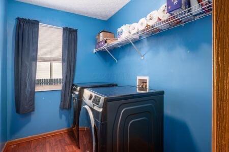 laundry area with baseboards, laundry area, wood finished floors, washer and dryer, and a textured ceiling