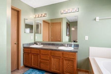 bathroom featuring a sink, a garden tub, and double vanity