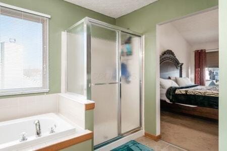 ensuite bathroom with a textured ceiling, a shower stall, a garden tub, and connected bathroom