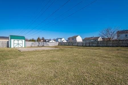 view of yard featuring a storage shed, an outdoor structure, and fence