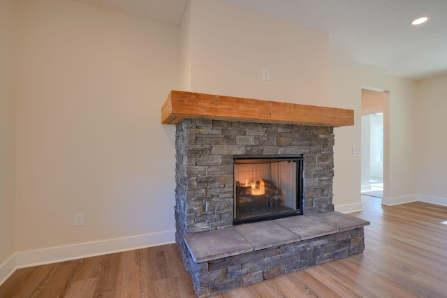 room details featuring recessed lighting, baseboards, a stone fireplace, and wood finished floors