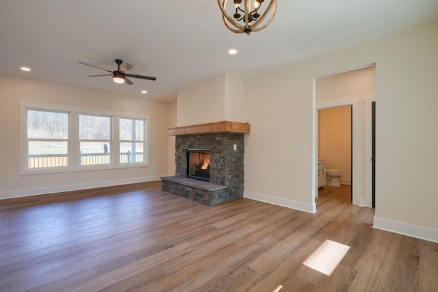 unfurnished living room featuring a stone fireplace, recessed lighting, baseboards, and wood finished floors