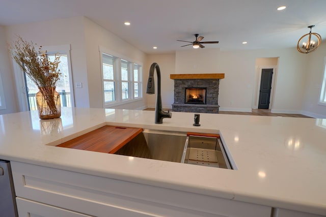 kitchen featuring recessed lighting, baseboards, a fireplace, and ceiling fan with notable chandelier