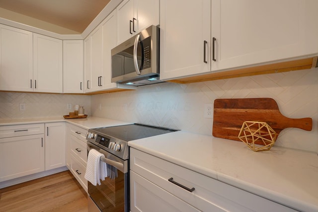 kitchen featuring tasteful backsplash, white cabinetry, and stainless steel appliances