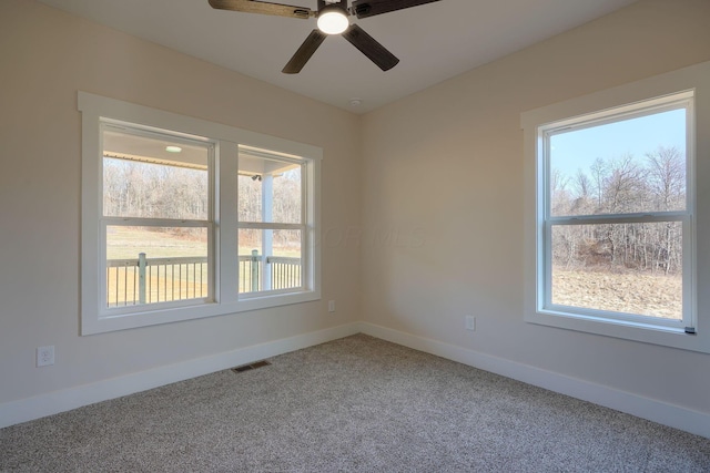 spare room with visible vents, plenty of natural light, carpet flooring, and baseboards