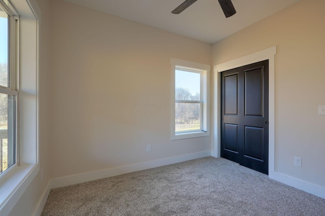 carpeted empty room featuring a ceiling fan and baseboards