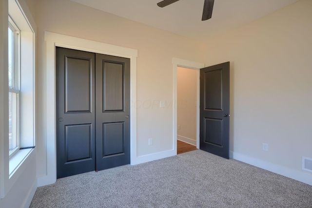 unfurnished bedroom with a ceiling fan, visible vents, carpet, baseboards, and a closet