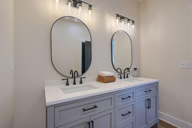 bathroom featuring double vanity, baseboards, and a sink