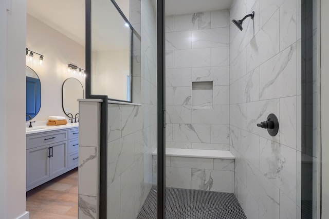 full bath with wood finished floors, vanity, and a tile shower