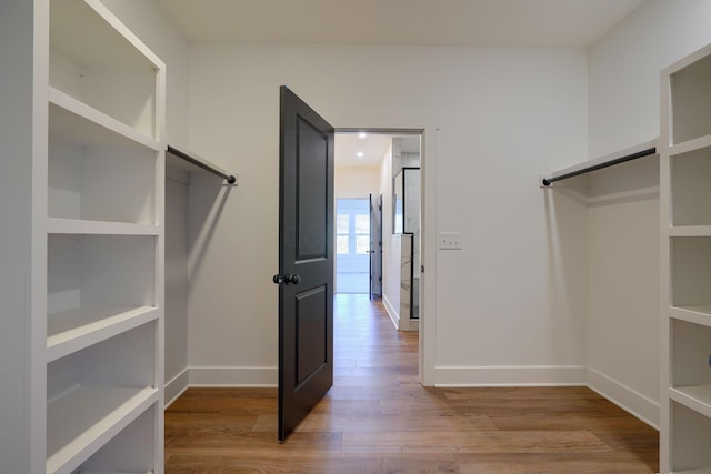 walk in closet with wood finished floors