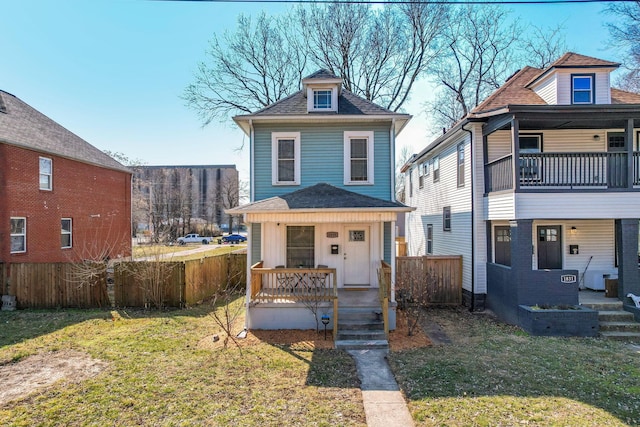 view of front of home with a porch, roof with shingles, a front lawn, and fence