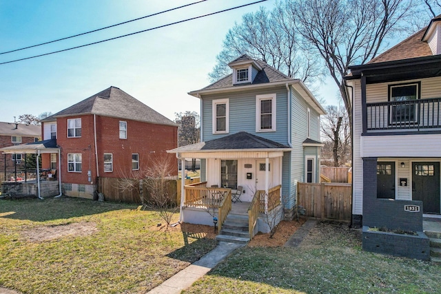 traditional style home with covered porch, a shingled roof, a front yard, and fence