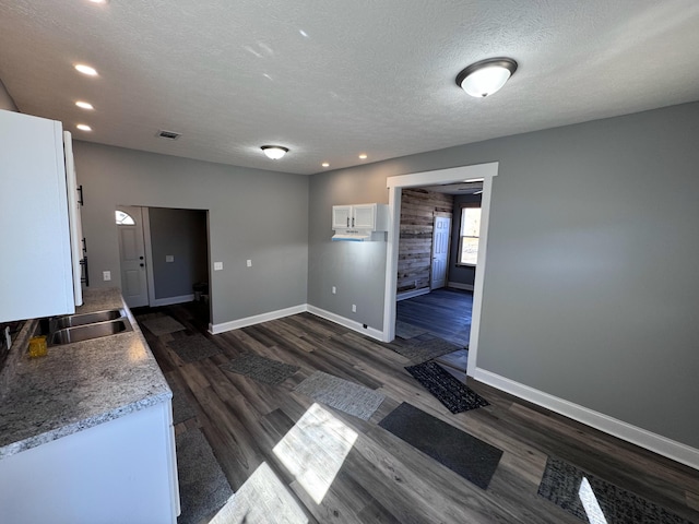 interior space featuring a sink, visible vents, baseboards, and dark wood-style flooring