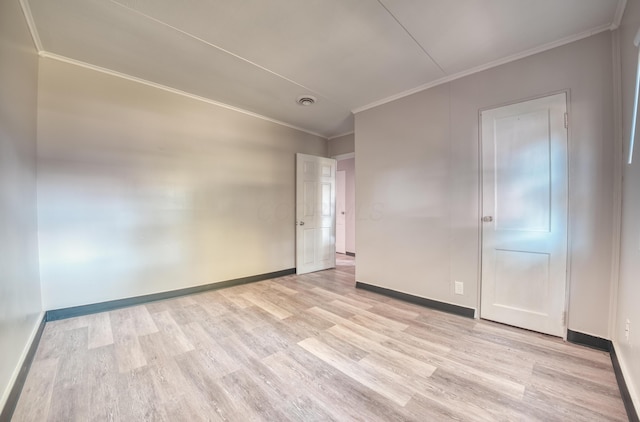 spare room featuring crown molding, baseboards, and light wood-type flooring