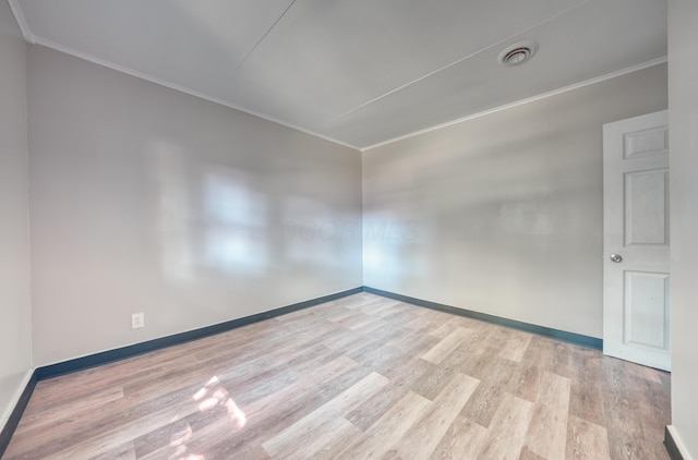 empty room featuring visible vents, wood finished floors, and ornamental molding