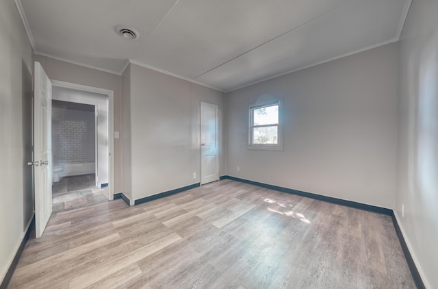 interior space featuring light wood-type flooring, baseboards, visible vents, and ornamental molding