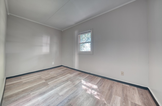 unfurnished room featuring baseboards, wood finished floors, and crown molding