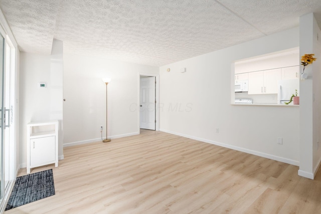 unfurnished room with a textured ceiling, baseboards, and light wood-style floors