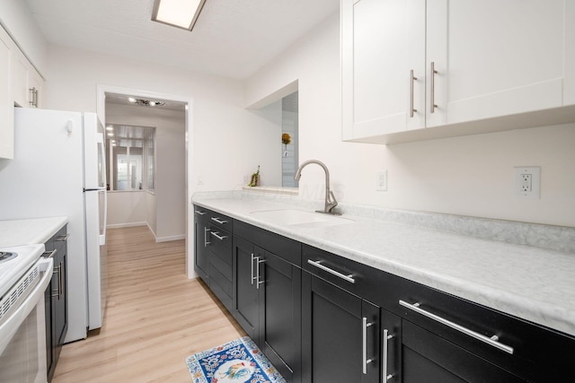 kitchen with white cabinetry, light wood-type flooring, light countertops, and a sink