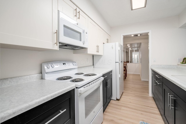 kitchen with white appliances, dark cabinetry, light countertops, and white cabinetry