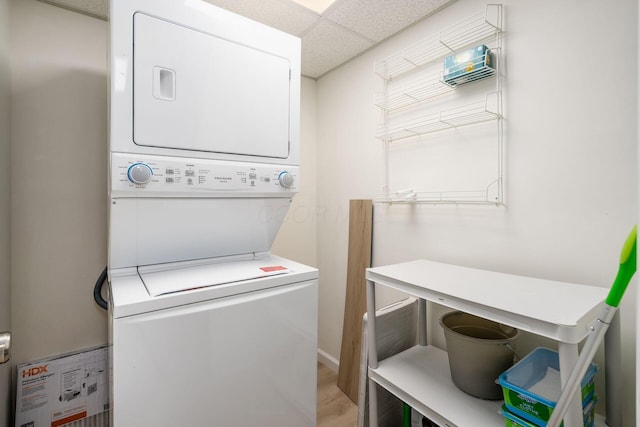 washroom with laundry area, stacked washer and dryer, and water heater