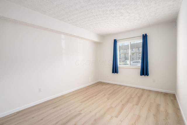 empty room with wood finished floors, baseboards, and a textured ceiling