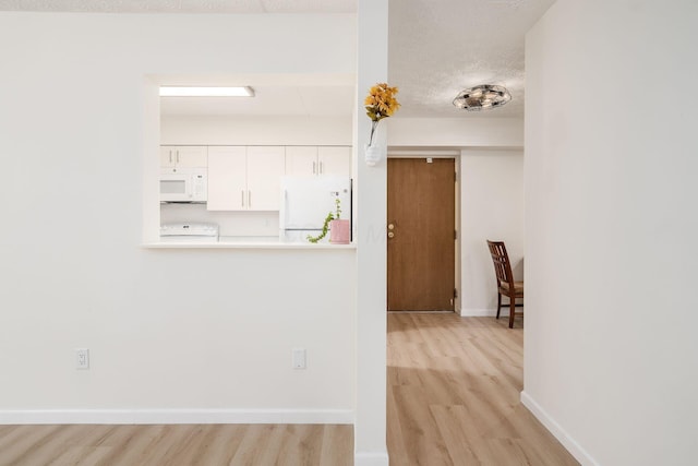 interior space with baseboards, light wood finished floors, and a textured ceiling