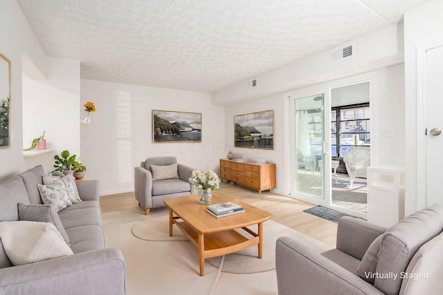 living area featuring visible vents, a textured ceiling, and light wood-style flooring