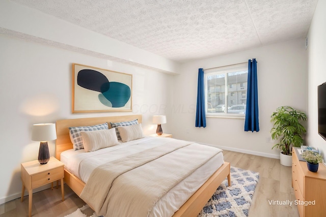 bedroom featuring wood finished floors, baseboards, and a textured ceiling