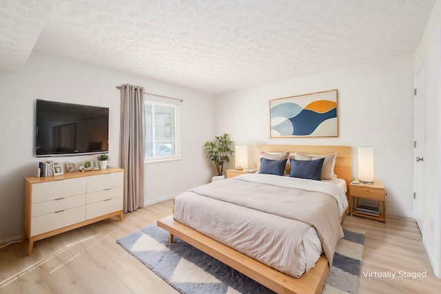 bedroom featuring light wood-style floors, baseboards, and a textured ceiling