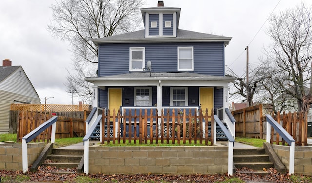 traditional style home with a porch, stairs, and fence