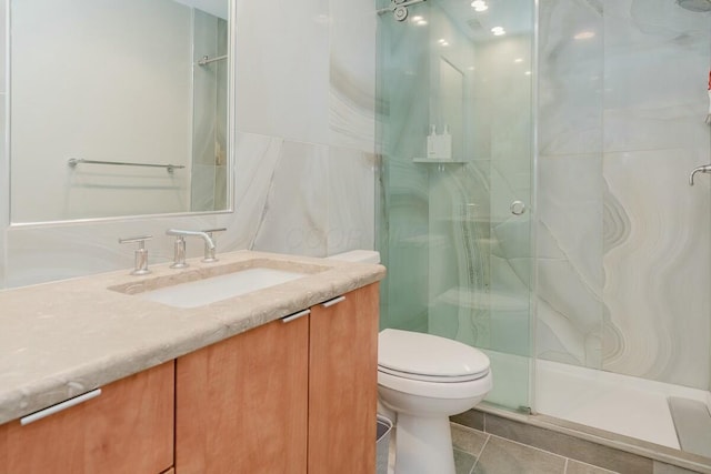 bathroom featuring tile patterned floors, vanity, toilet, and a shower stall