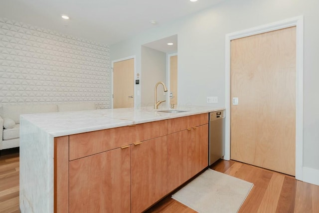 kitchen featuring light stone countertops, light wood-style flooring, recessed lighting, a sink, and stainless steel dishwasher