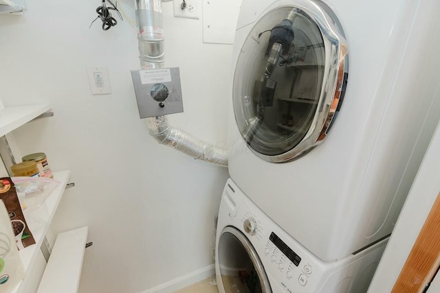 washroom featuring laundry area, stacked washing maching and dryer, and baseboards