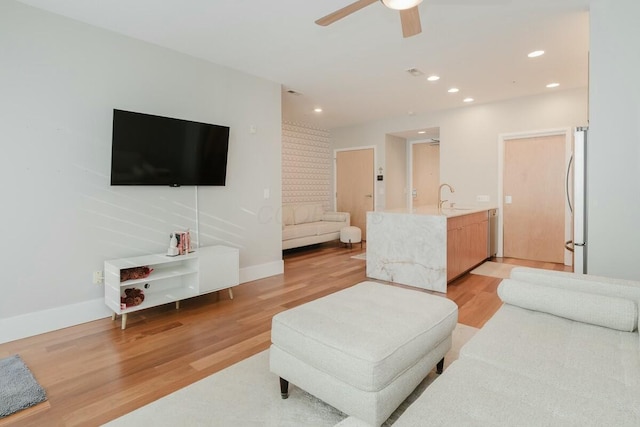 living area with recessed lighting, light wood-style flooring, a ceiling fan, and baseboards