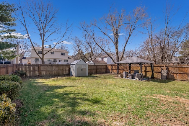 view of yard with a gazebo, a shed, an outbuilding, and a fenced backyard