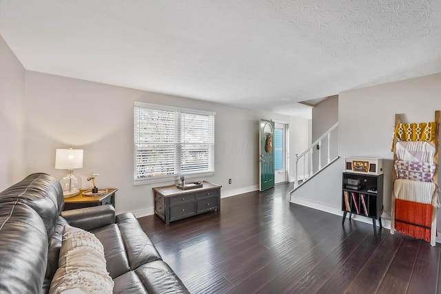 living area featuring baseboards, a textured ceiling, dark wood finished floors, and stairs