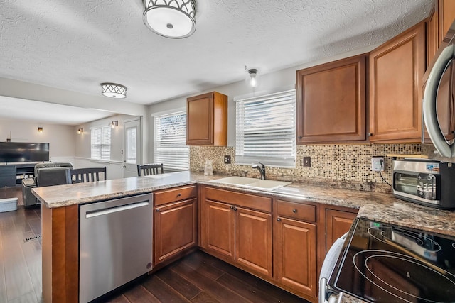 kitchen featuring range with electric cooktop, dark wood-type flooring, a sink, stainless steel dishwasher, and a peninsula