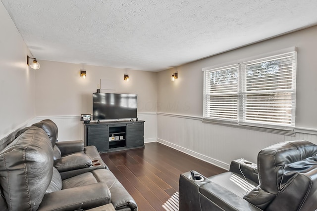 living area featuring a textured ceiling, dark wood-style floors, and wainscoting