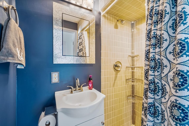 bathroom featuring tiled shower and vanity