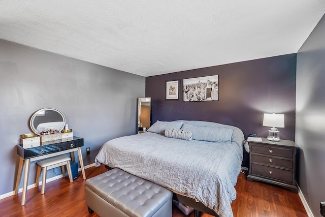 bedroom featuring wood finished floors, baseboards, and a textured ceiling