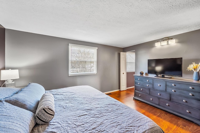 bedroom with baseboards, dark wood-style flooring, and a textured ceiling