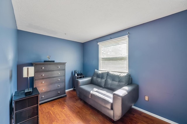 living area featuring baseboards, a textured ceiling, and wood finished floors