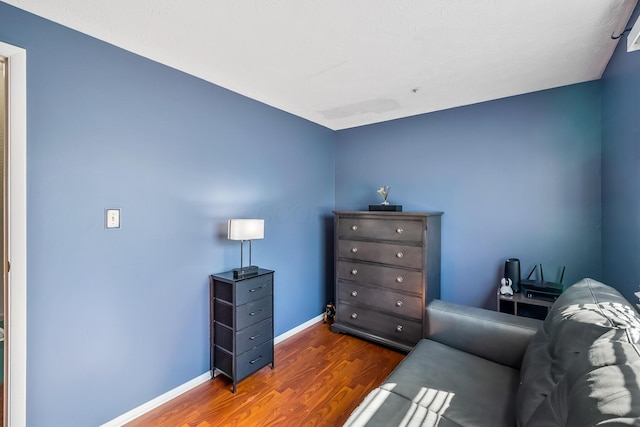 living area with baseboards and wood finished floors