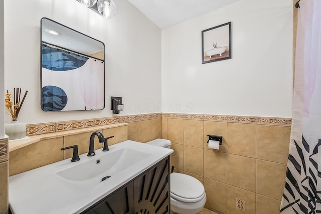 full bath featuring toilet, curtained shower, tile walls, wainscoting, and vanity