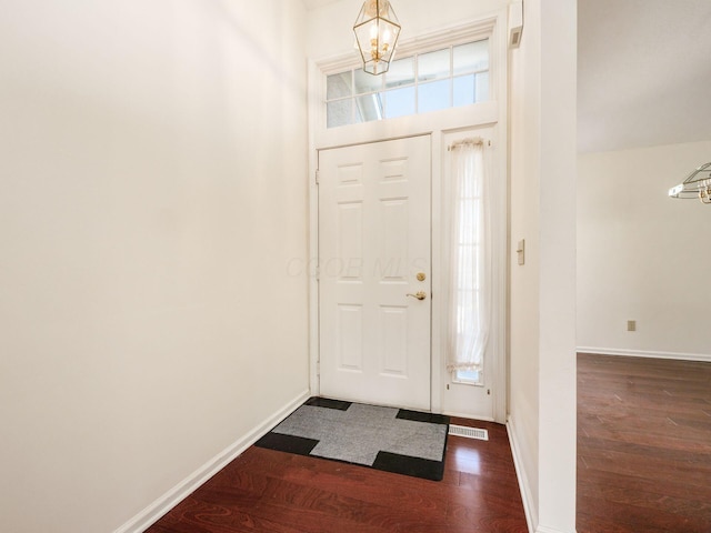 entryway with visible vents, baseboards, a notable chandelier, and dark wood-style flooring