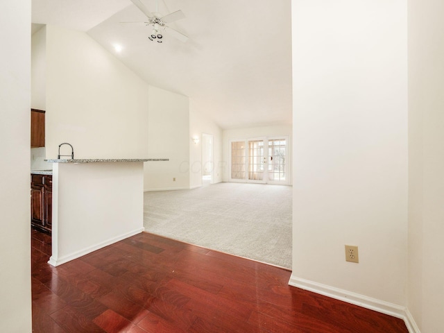 unfurnished living room featuring dark wood-style floors, baseboards, high vaulted ceiling, ceiling fan, and dark colored carpet