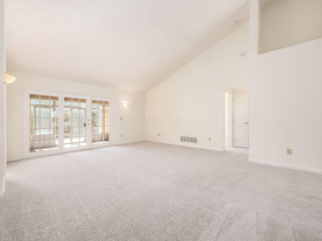 empty room featuring visible vents, light colored carpet, high vaulted ceiling, and baseboards